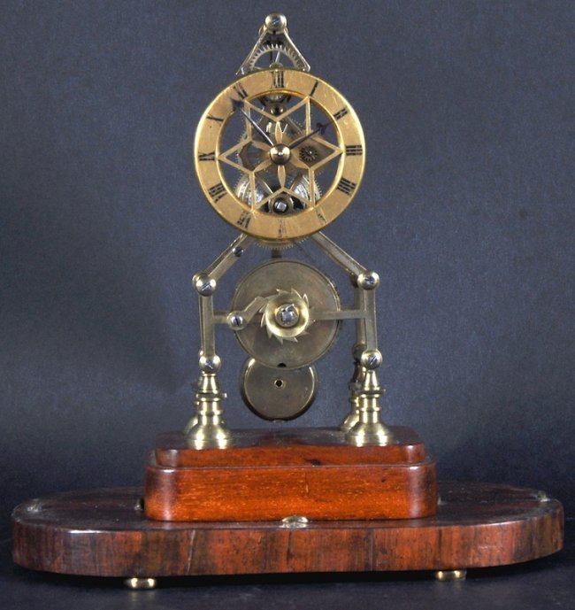 A BRASS SKELETON CLOCK in a glass dome. 6.5 inches.