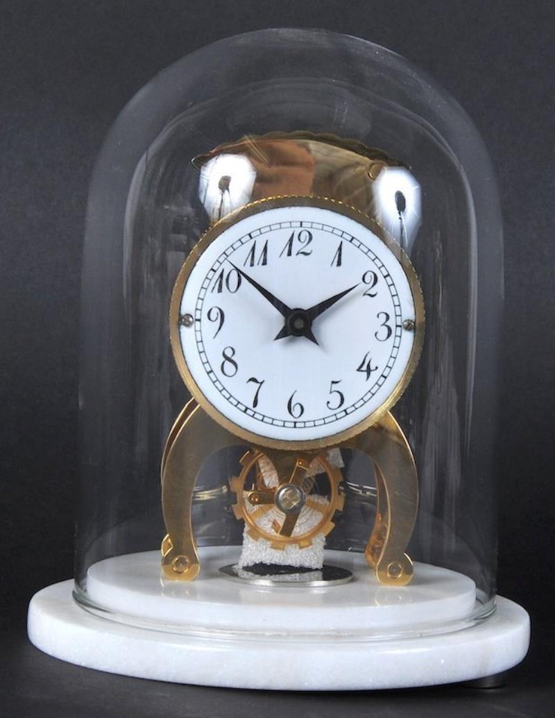 A WEHRLE BRASS CLOCK in a glass dome on a white marble