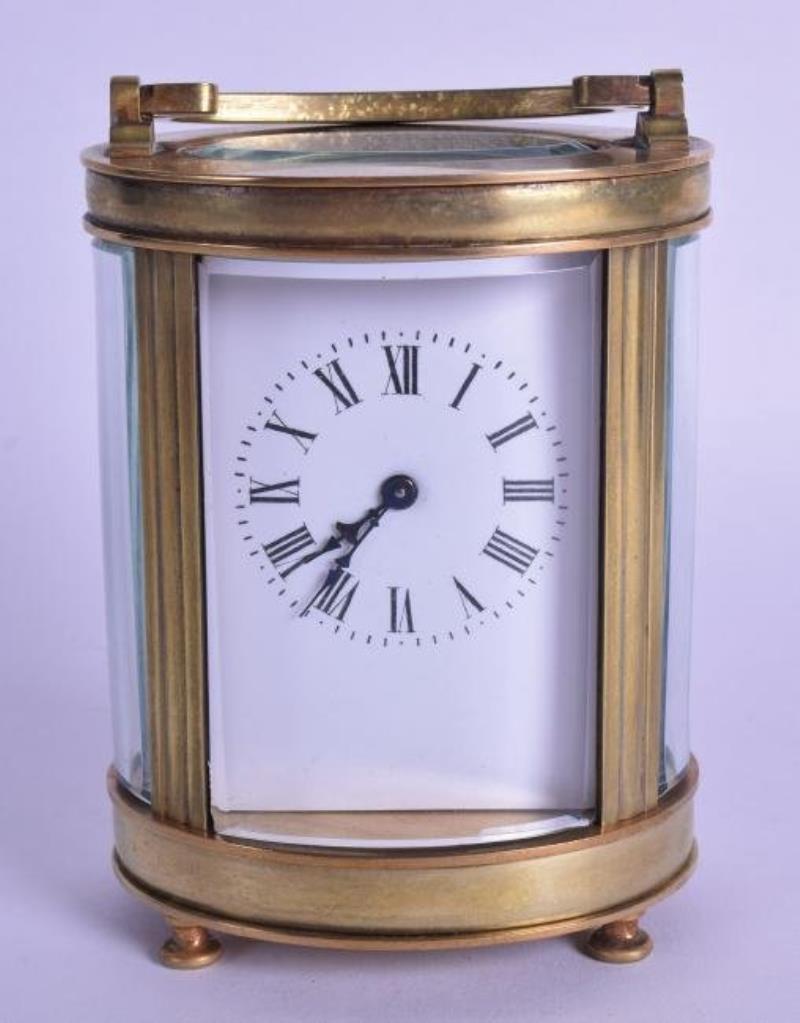 A FRENCH BRASS OVAL CARRIAGE CLOCK with white enamel